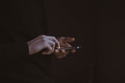 silhouette photo of person holding smartphone