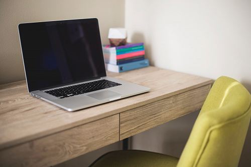 silver and black laptop computer on brown wooden desk beside green leather chair