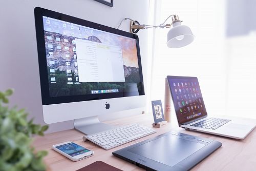 silver iMac near iPhone on brown wooden table