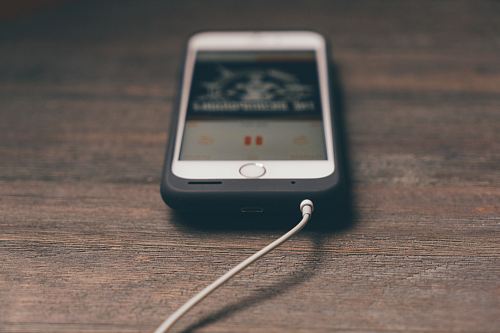 silver iphone with black case on brown surface