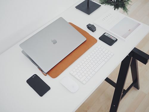 silver MacBook and phone on white table