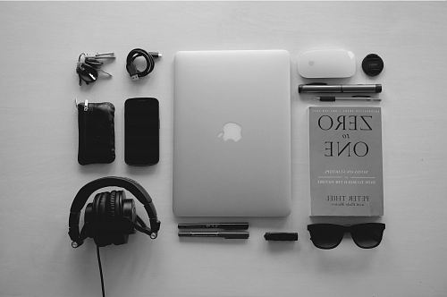 silver MacBook near black corded headphones and assorted items
