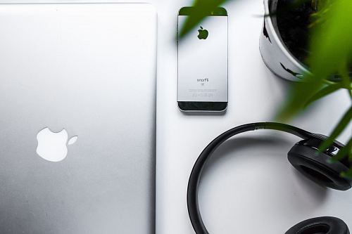 space gray iPhone SE beside headphones and silver MacBook