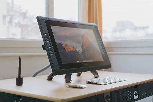 turned on gray flat screen monitor on wooden desk