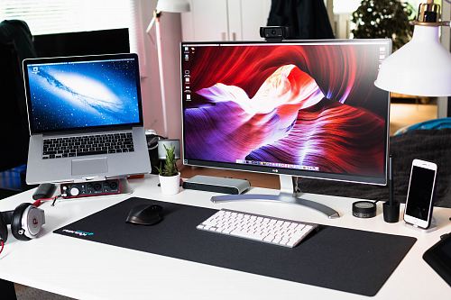 turned on MacBook Pro beside monitor on desk