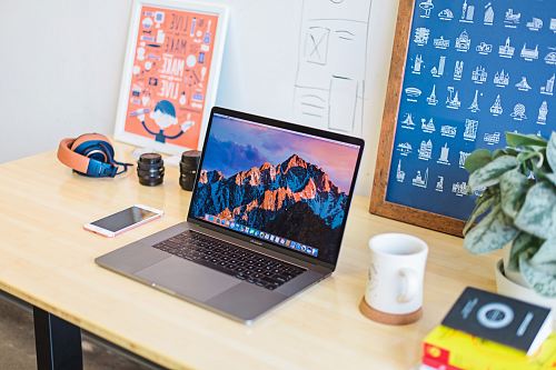 turned on MacBook Pro beside white ceramic mug