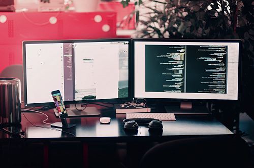 two black computer monitors on black table