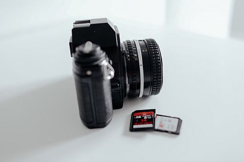 two black memory cards beside black DSLR camera on white surface