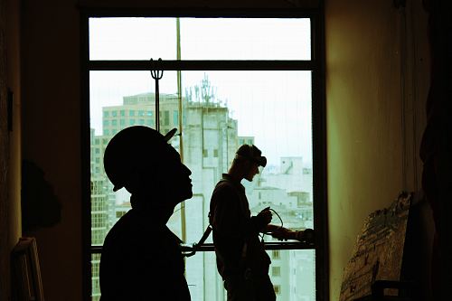 two men wearing hard hat standing near clear glass window