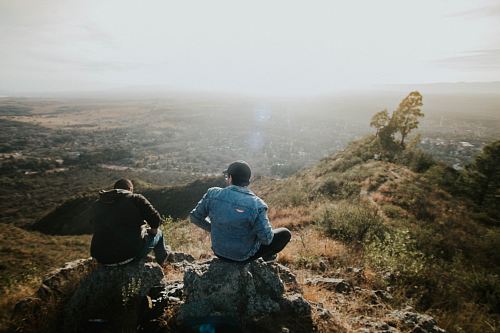 two person sitting on rock