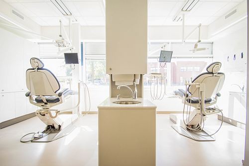 two white dentist chairs inside white painted room