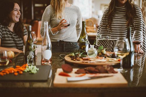two woman standing beside woman sitting in front of table