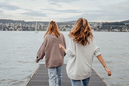two women standing on dock front of sea at daytime