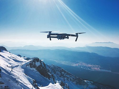 white quadcopter drone flying near snow mountain during daytime