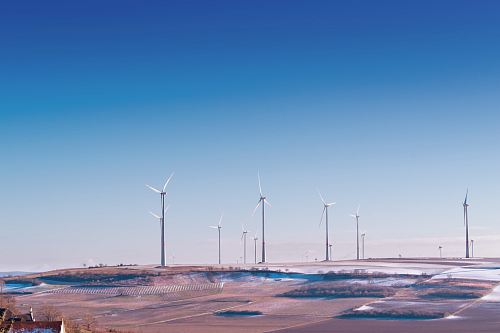 white wind turbine on grey desert under blue and white sky