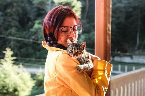 woman carrying cat while standing on porch