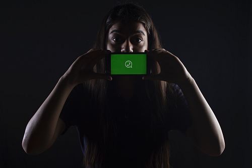 woman holding black smartphone at Whatsapp logo