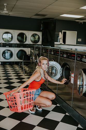 woman kneeling in front of front-load clothes washer inside laundry shop