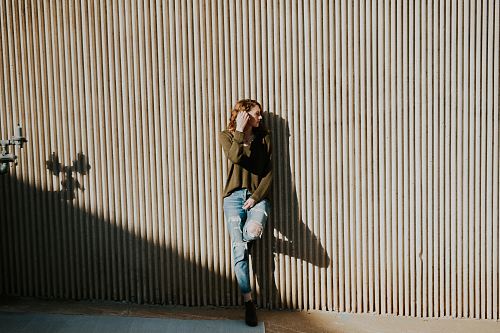 woman leaning on beige wall with shadow at daytime
