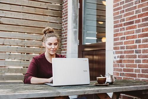 woman sitting and holding white Acer laptop near brown wooden wall