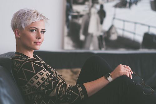 woman sitting on sofa holding eyeglasses