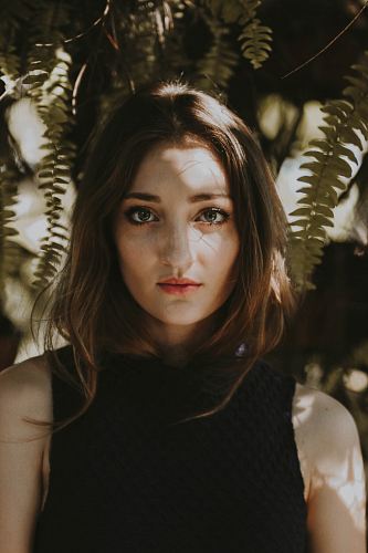 woman standing near fern plant
