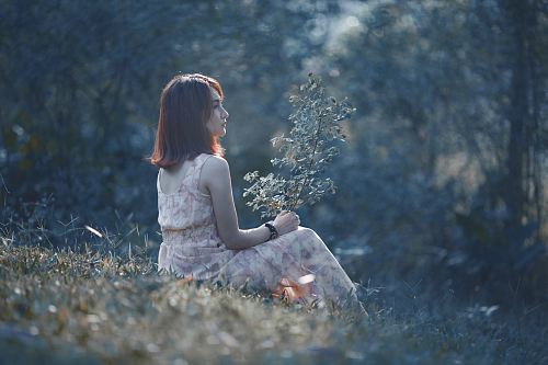 woman wearing floral dress sitting on green grass outdoor