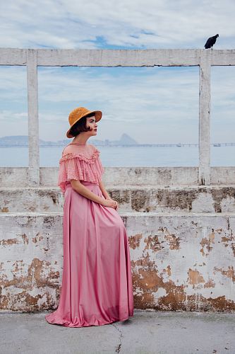 woman wearing pink dress standing next to white wall
