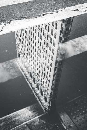  grayscale photography of reflection of building on body of water 