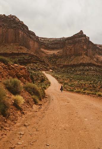 nature person walking on walkway near mountains outdoors