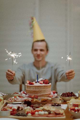 cake selective focus photography of man holding sparklers between cake dessert