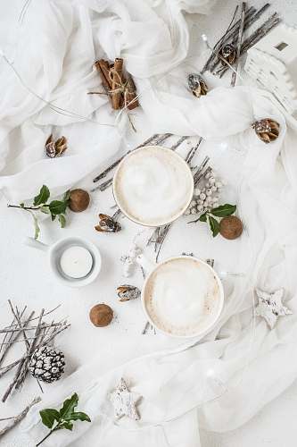food two white ceramic cups on white textle leaf