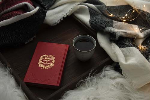 book white ceramic coffee mug with coffee besides red envelope cup