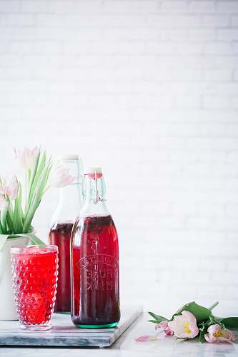 drink clear glass bottle beside purple flowers flower