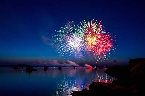 fireworks green, red, and white fireworks on sky at nighttime water