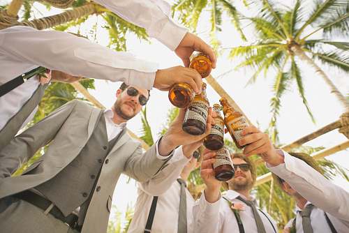person low angle of men holding beer bottles and having a toast wedding