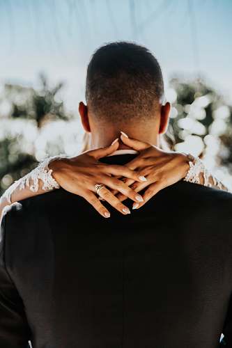 human bride with hands on back of man wearing black formal top wedding