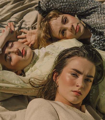 human three women lying on white surface furniture