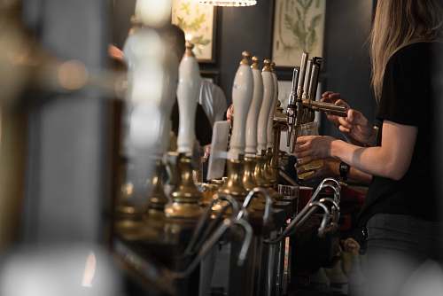 human woman holding cup beside beer tap handles pub