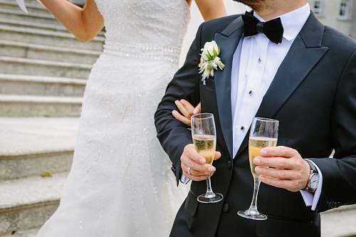 suit man holding two champagne flutes near woman tuxedo