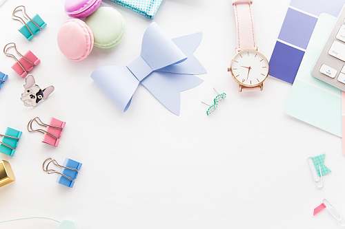 pastel round white and gold-colored analog watch beside paper ribbon styled stock