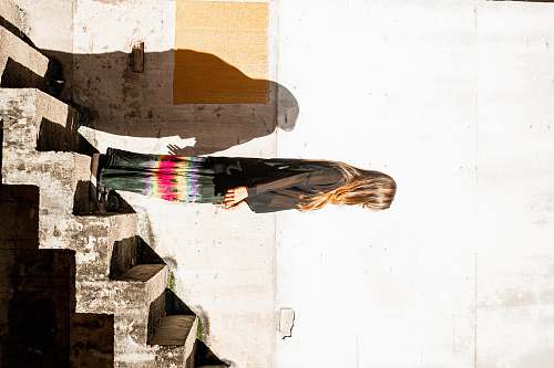 animal woman in black long sleeved shirt and multicolored skirt standing on stairs bird