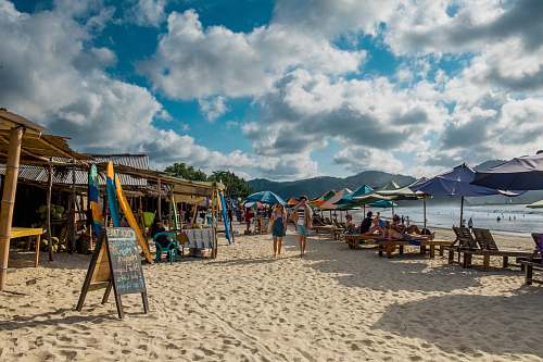 coast two person walking on beach with assorted umbrellas and nipa huts sea