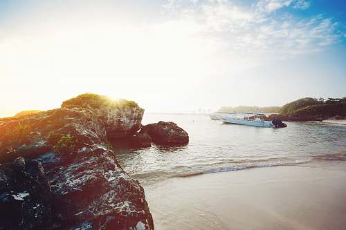 water white boat near seashore during daytime sea