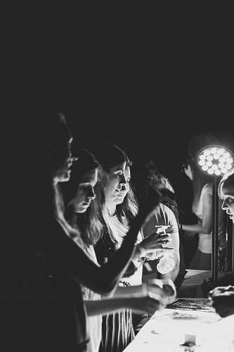human grayscale photography of women standing near table person