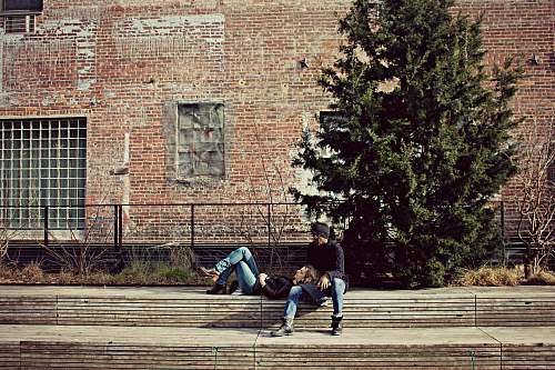 building photo of woman laying on man's lap near green leafed tree human