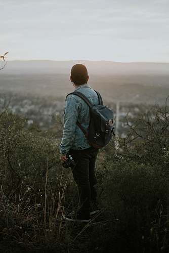 person man carrying grey leather backpack people