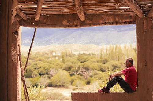 person person sitting on concrete rail near green grass during daytime people