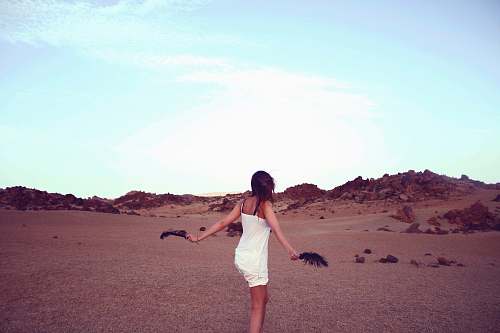 people woman in white dress holding black feathers woman