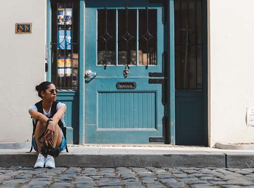 person woman sitting near blue door people